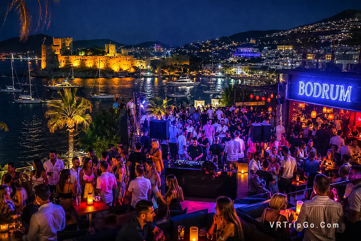 Nightlife in Bodrum luxury beach club party with vibrant crowd, neon lights and marina view at night in Turkey