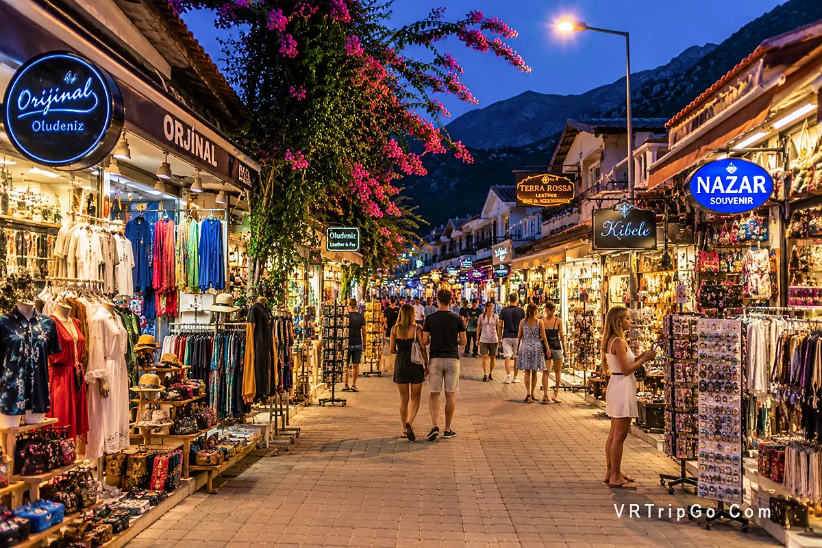 Shopping in Oludeniz with vibrant evening market street, souvenir shops, local boutiques and lively Mediterranean resort atmosphere at night.