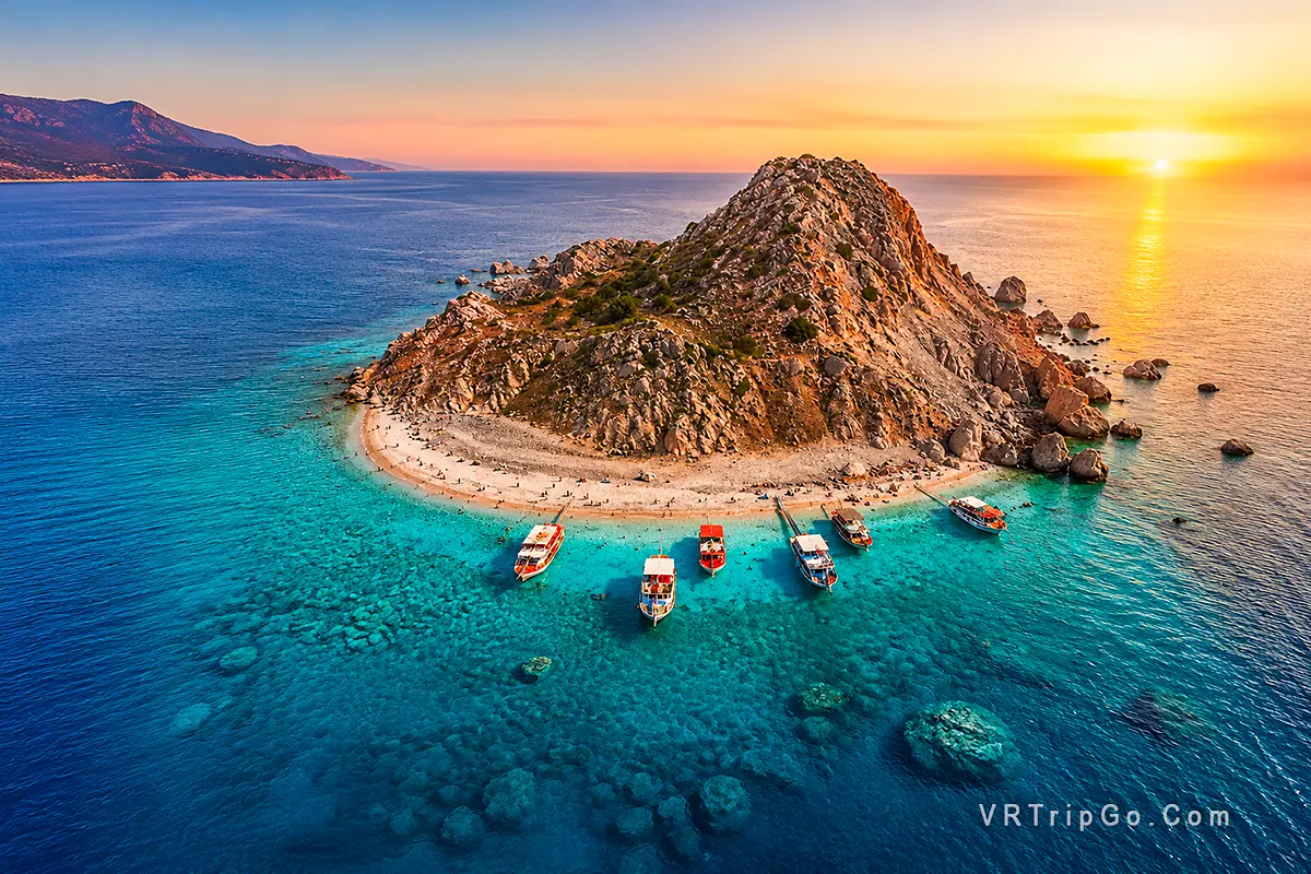 Suluada Island Boat Tour featuring the famous white beach of Suluada, crystal-clear turquoise waters, excursion boats lined along the shore, and breathtaking Mediterranean island scenery at sunset