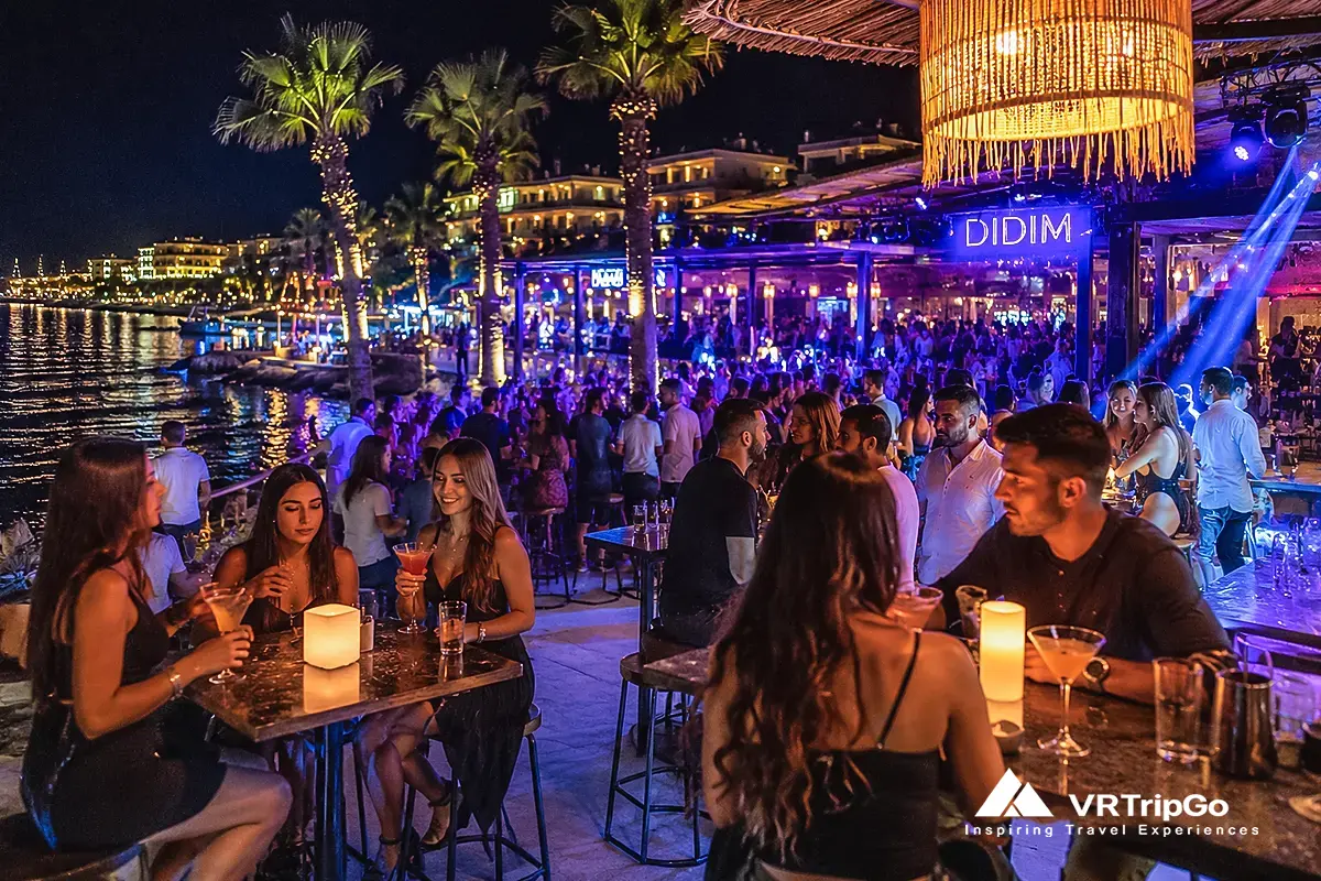Vibrant nightlife in Didim with beachfront bars, live music, palm trees, and visitors enjoying an evening by the sea.