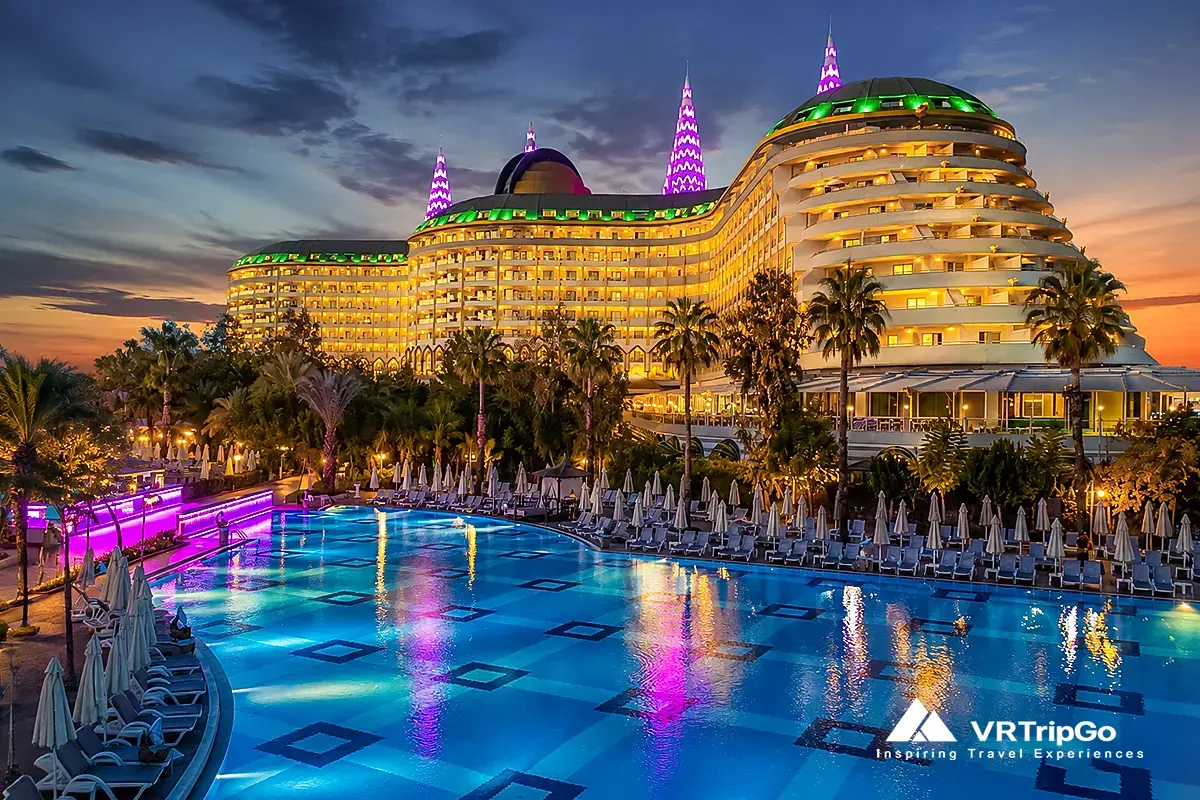 Best hotels in Antalya with luxury beachfront resort, large swimming pool and illuminated hotel at sunset, premium accommodation in Antalya Turkey