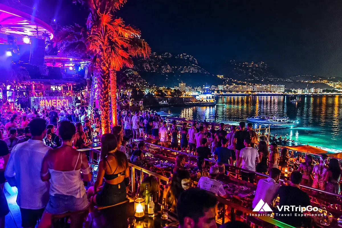 Nightlife in Antalya with vibrant beach club, neon lights, live music and crowded terrace by the sea, exciting nightlife atmosphere in Antalya Turkey