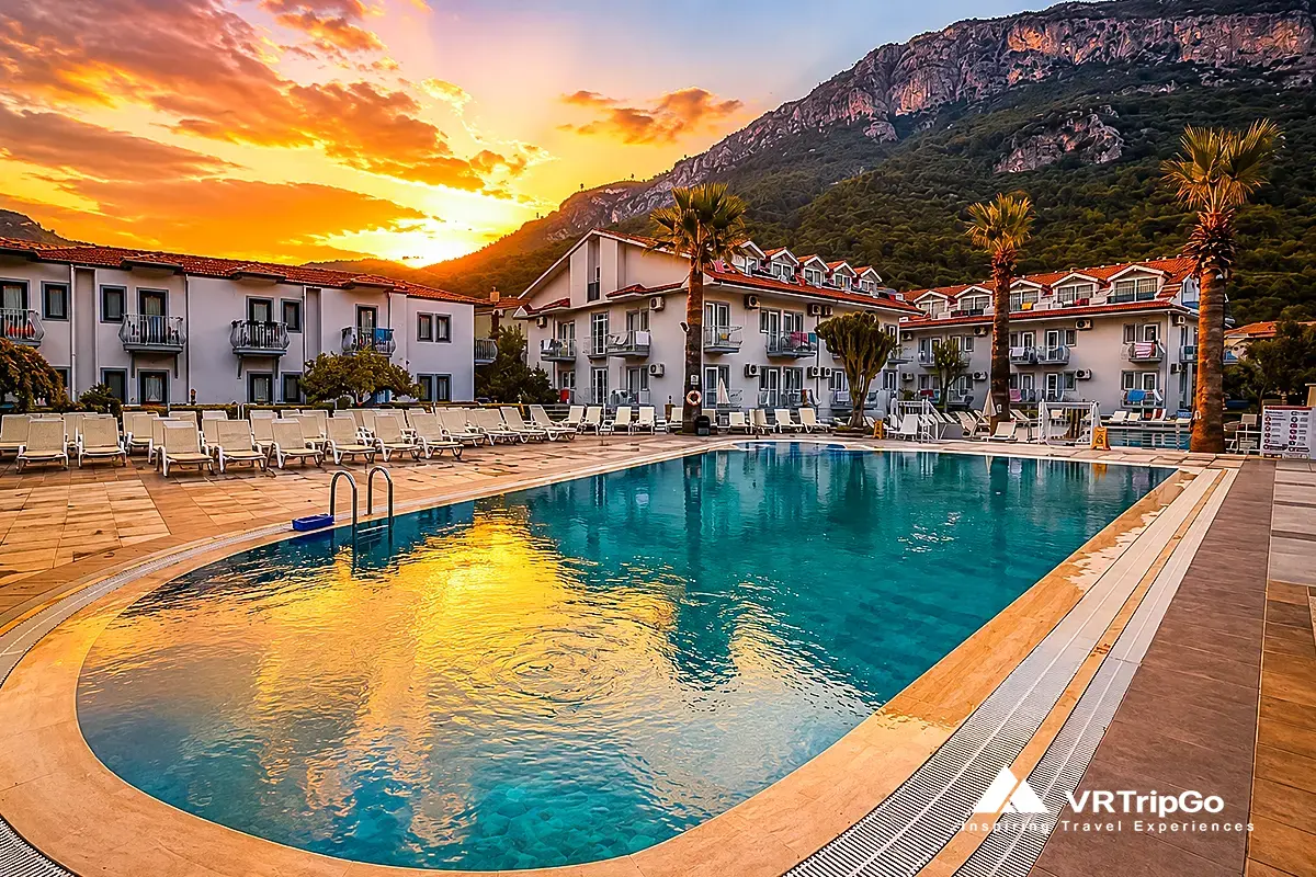 Luxury resort pool at sunset in Oludeniz with mountain views, modern accommodation and relaxing atmosphere near the Mediterranean coast.