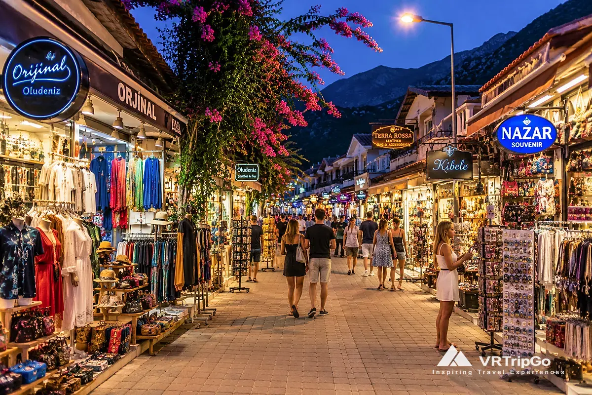 Shopping in Oludeniz with vibrant evening market street, souvenir shops, local boutiques and lively Mediterranean resort atmosphere at night.