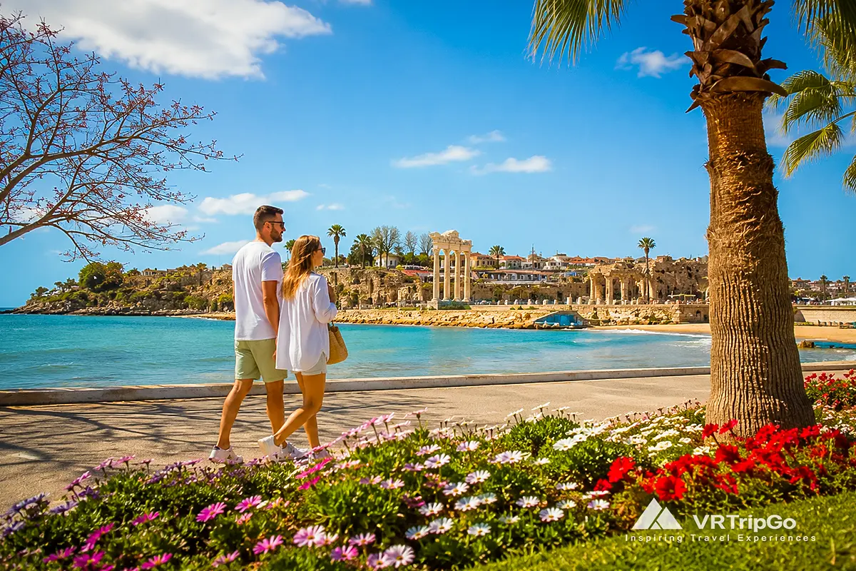 Side Weather in Spring: Couple Walking Along the Seafront Promenade Near the Temple of Apollo During a Sunny Spring Day in Side, Turkey
