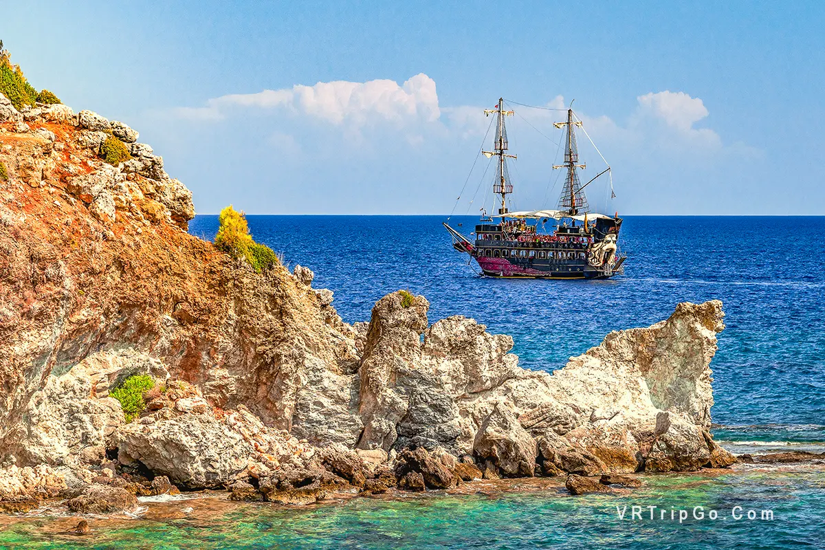 Pirate Boat Tour from Kemer featuring a pirate-themed excursion ship sailing along the rocky Mediterranean coastline, crystal-clear turquoise waters, and spectacular sea views near Kemer.
