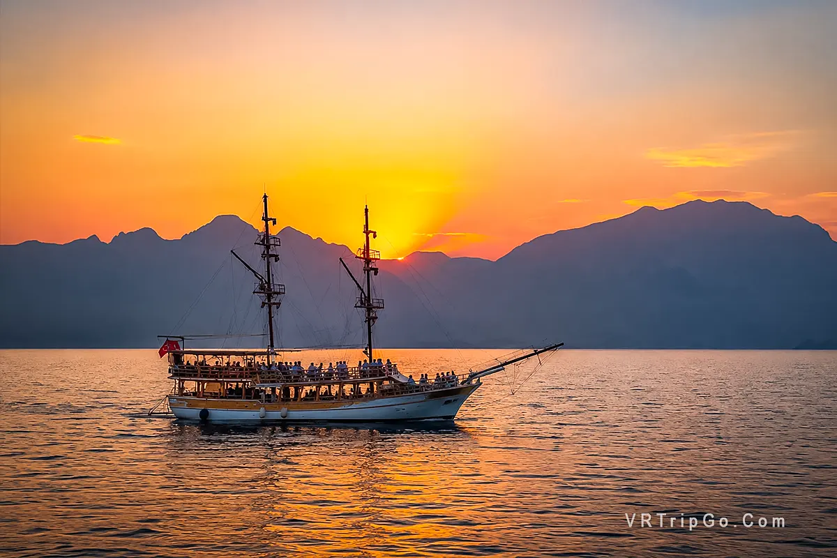Best Excursions in Side featuring a traditional excursion boat, stunning Mediterranean sunset, and breathtaking coastal scenery along the Turkish Riviera.
