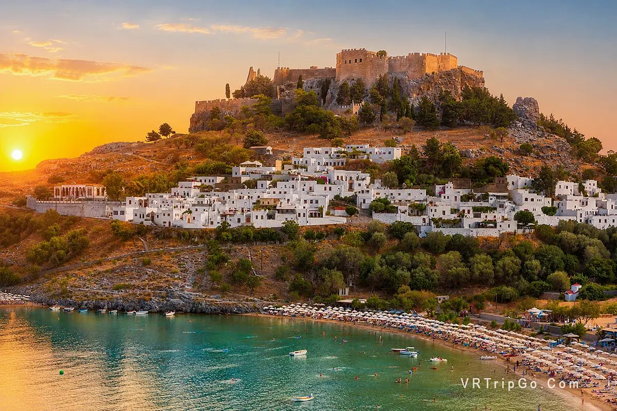 Rhodes Island Day Trip featuring the iconic Lindos Acropolis, whitewashed hillside houses, and a beautiful beach at sunset on Rhodes Island.