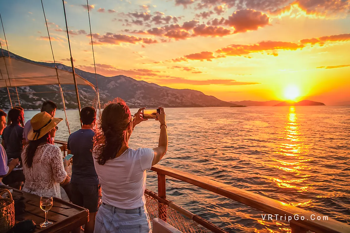 Altinkum Sunset Cruise with Guests Photographing a Spectacular Aegean Sunset from the Boat Deck