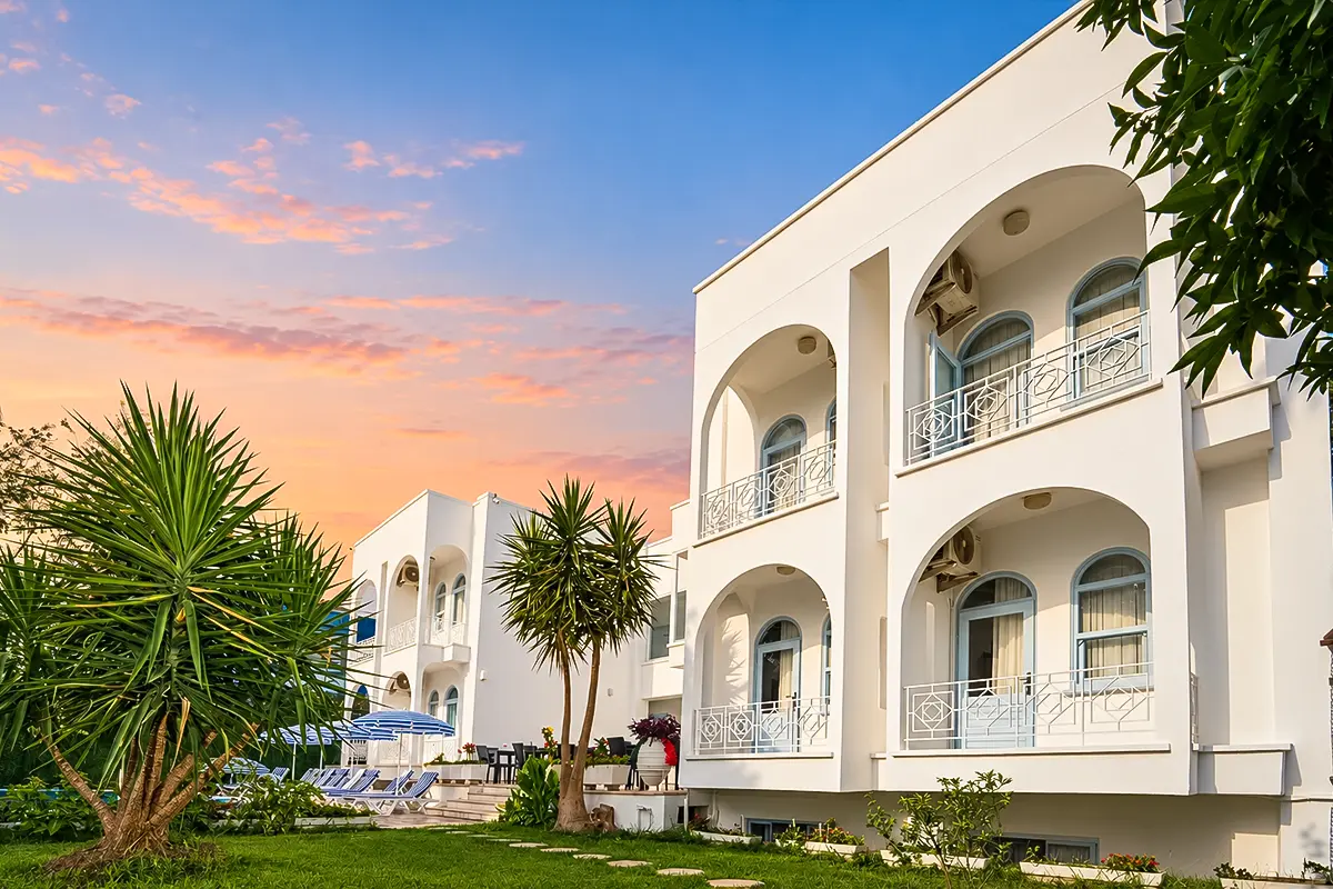 Kemer Royal Beach Hotel, a budget-friendly option among Cheap Hotels in Kemer, with white arched balconies and a landscaped garden.