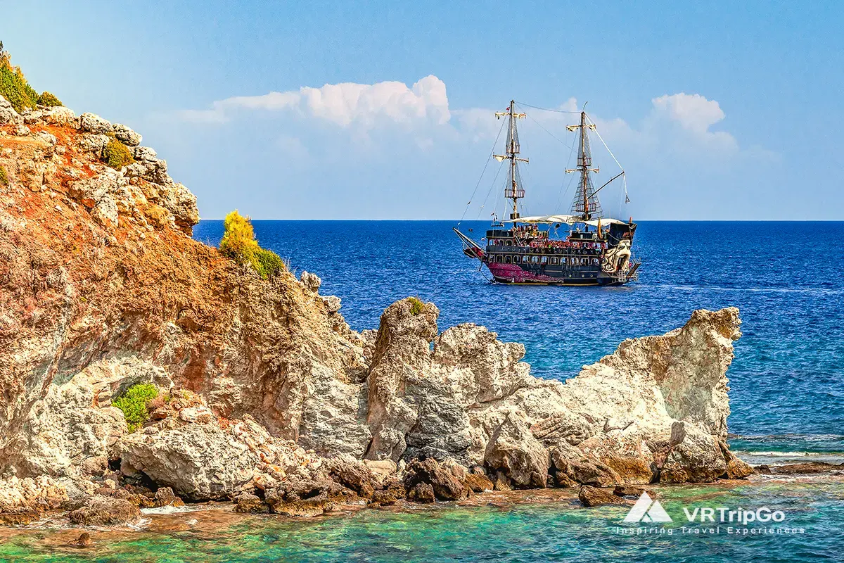 Pirate Boat Tour from Kemer featuring a pirate-themed excursion ship sailing along the rocky Mediterranean coastline, crystal-clear turquoise waters, and spectacular sea views near Kemer.