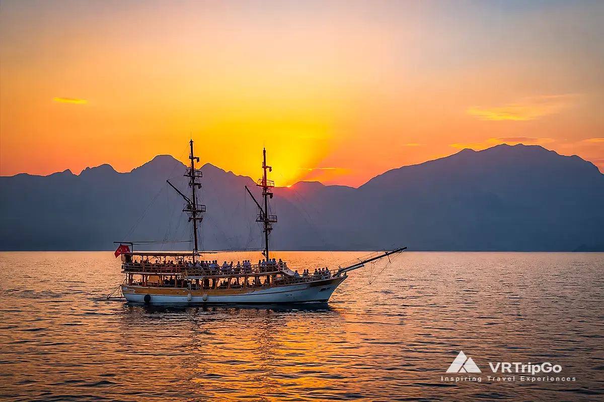 Best Excursions in Side featuring a traditional excursion boat, stunning Mediterranean sunset, and breathtaking coastal scenery along the Turkish Riviera.