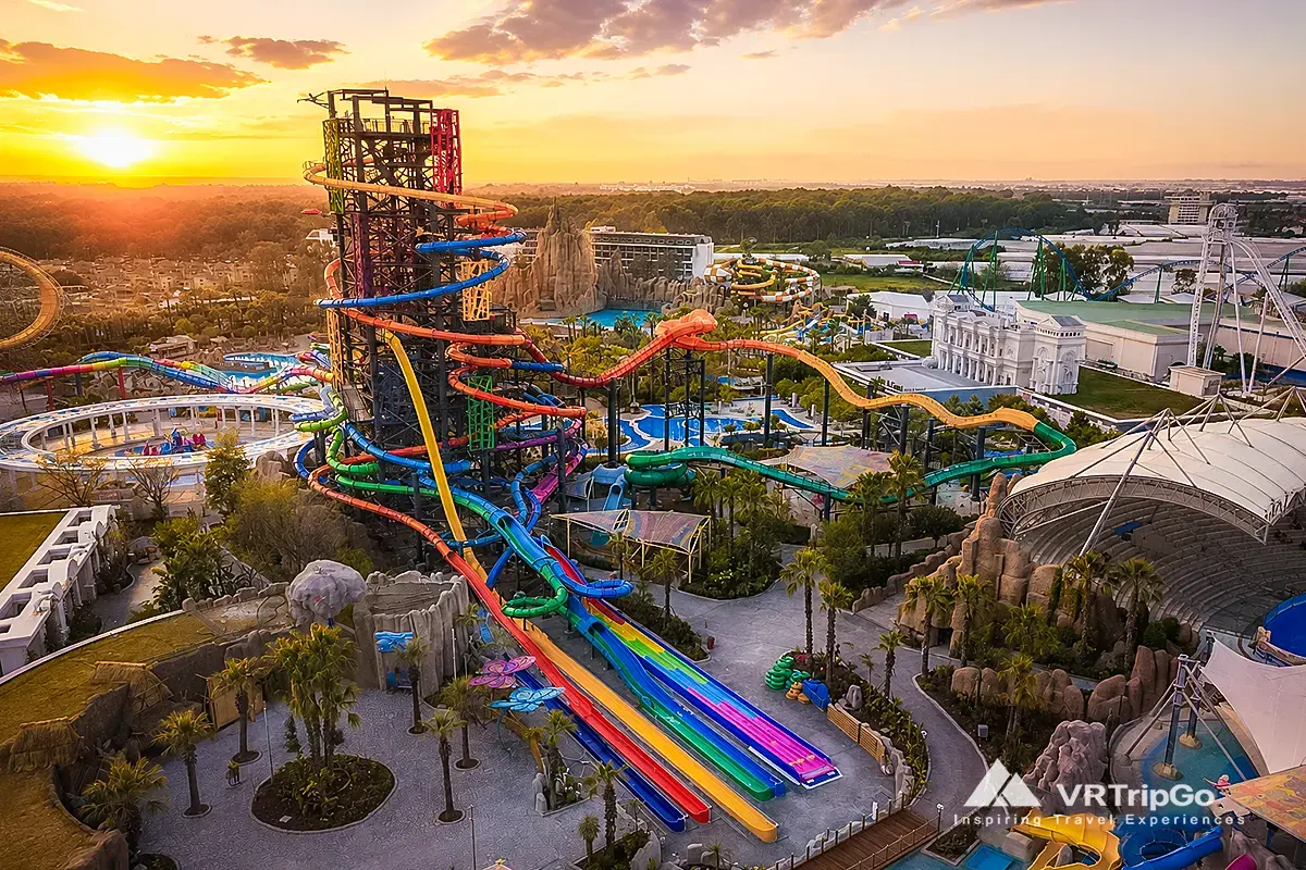 Land of Legends Theme Park Tour at sunset featuring colorful water slides, thrilling attractions, palm-lined pathways, and a spectacular aerial view of Turkey’s famous adventure park.