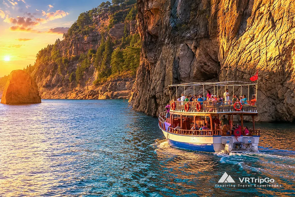 Green Canyon Boat Trip through dramatic cliffs and crystal-clear waters at sunset, featuring a traditional sightseeing boat, stunning canyon scenery, and a relaxing nature cruise experience.