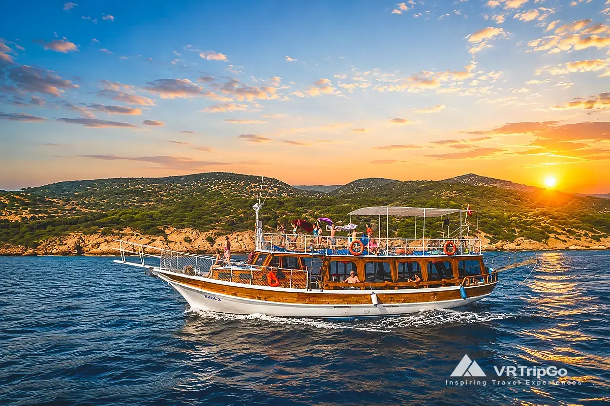 Bodrum Boat Tour featuring a traditional wooden boat cruising along the Bodrum coastline at sunset with crystal-clear Aegean waters and scenic coastal views.