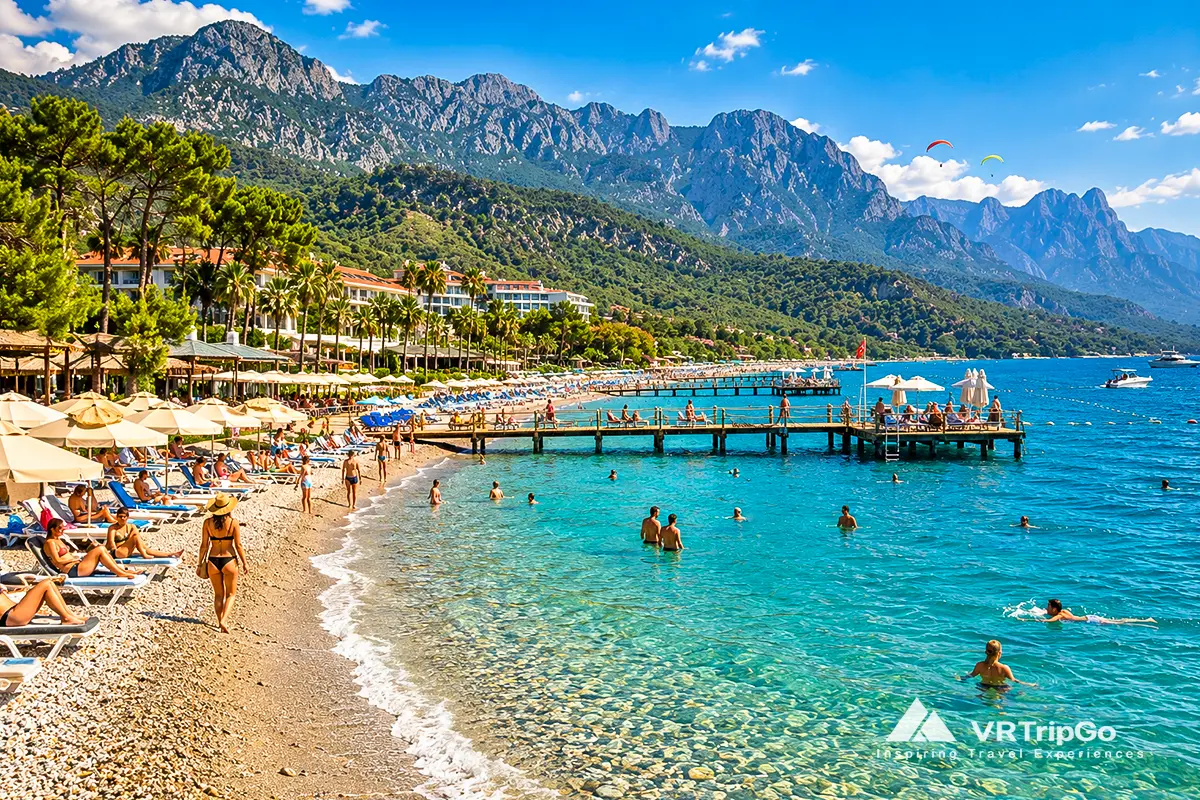 Goynuk Beach with turquoise waters, beach umbrellas, wooden piers, and scenic Taurus Mountains.